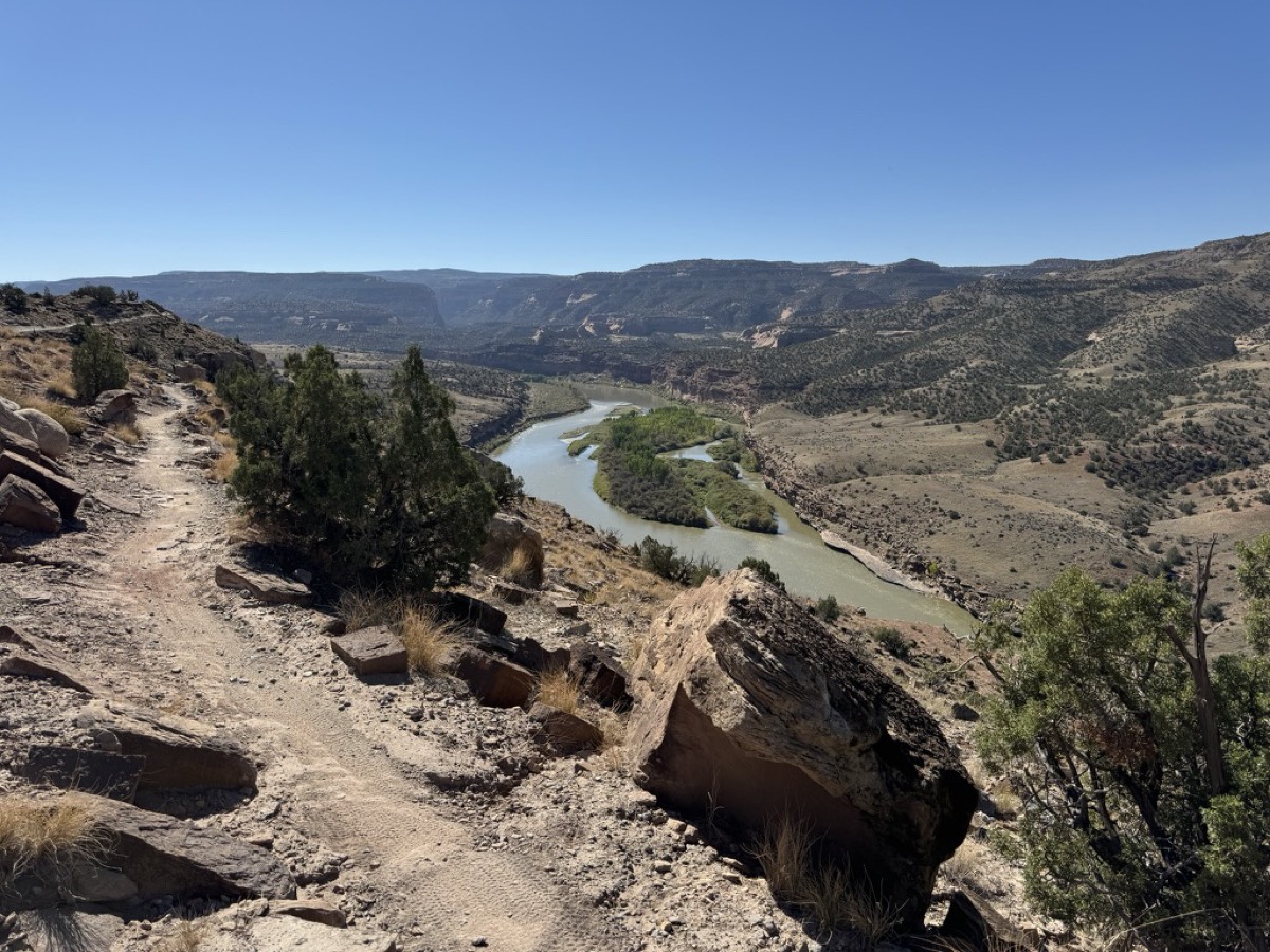 A trail dropping into a river valley, the road ahead out of sight
